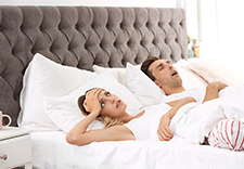 Chrapanie śpiącego mężczyzny na łóżku przeszkadza kobiecie
