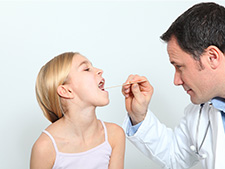 Pediatra sprawdza gardło dziewczynce- angina